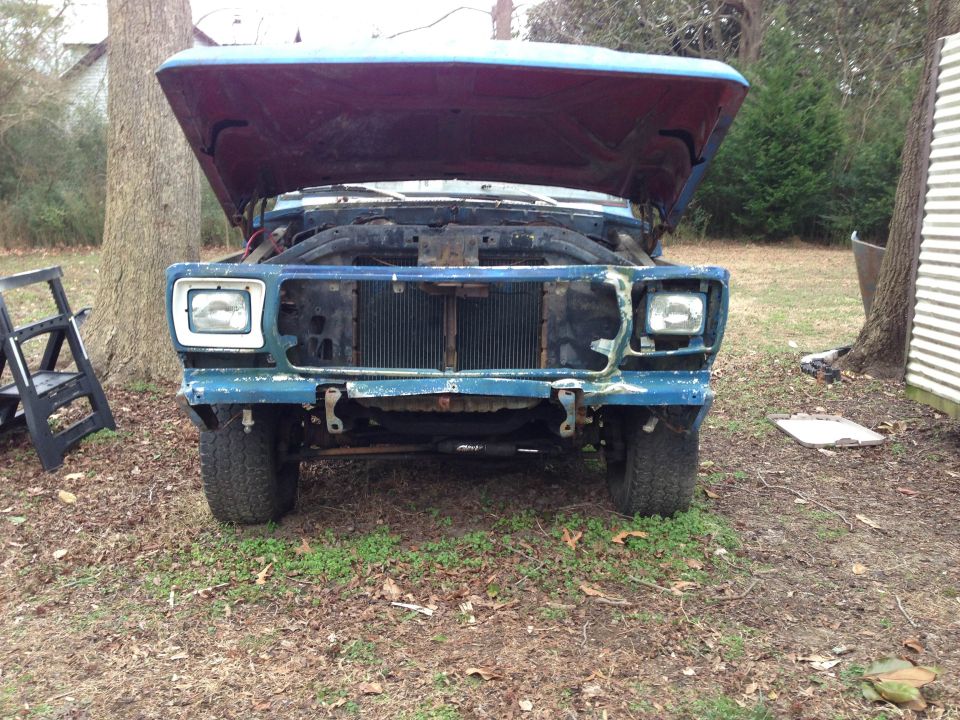 Blue SUV with hood open, showing grille and headlights. Front bumper is damaged