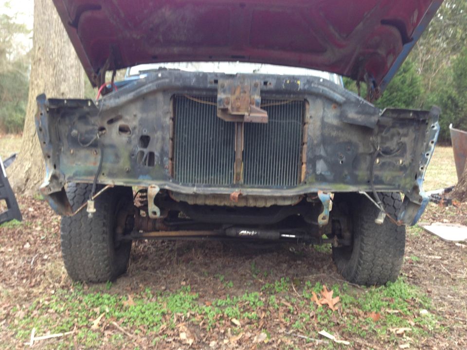 Front end of a vehicle with hood open, missing grille and bumper