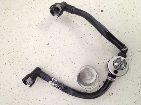2013 Ford Mustang - A close-up view of a fuel line assembly, including a filter or regulator, and a separate metal cap.