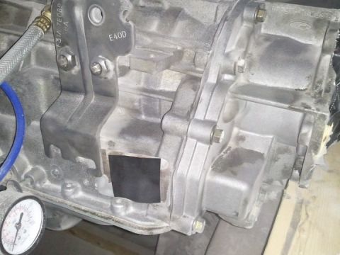 1994 Ford Bronco - Close-up of a transmission housing, showing bolted components and a pressure gauge.