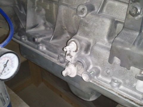 1994 Ford Bronco - A close-up view of a transmission housing, with a pressure gauge and blue hose attached to a component.