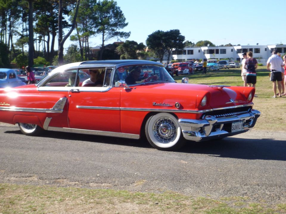 Red coupe with white roof and wide whitewall tires, chrome trim, and wire wheels. License plate reads 'SUNIVLY'