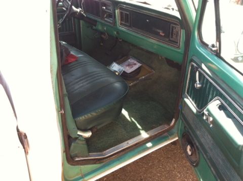 1977 Ford F-350 - The interior of a 1977 Ford F-350 shows a green dashboard and a dark green bench seat with a speaker in the door panel.