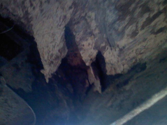 rock formations hanging from a cave ceiling, with a white stripe on the floor