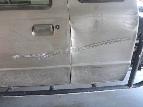 1997 Ford Ranger - The side of a truck shows extensive damage including deep scratches and a large dent on the rear door.