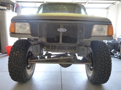 1997 Ford Ranger - Front view of a 1997 Ford Ranger, modified with large tires and a custom bumper, in a garage setting.