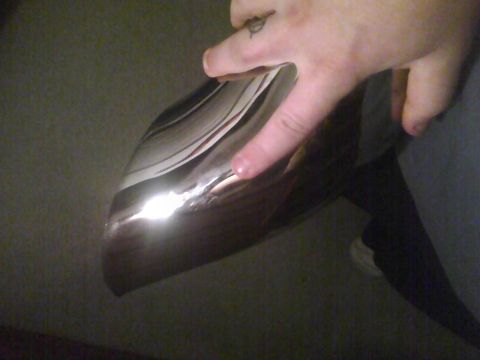 2003 Ford Crown Victoria - A close-up of a shiny chrome bumper, with a person's fingers visible on its surface.