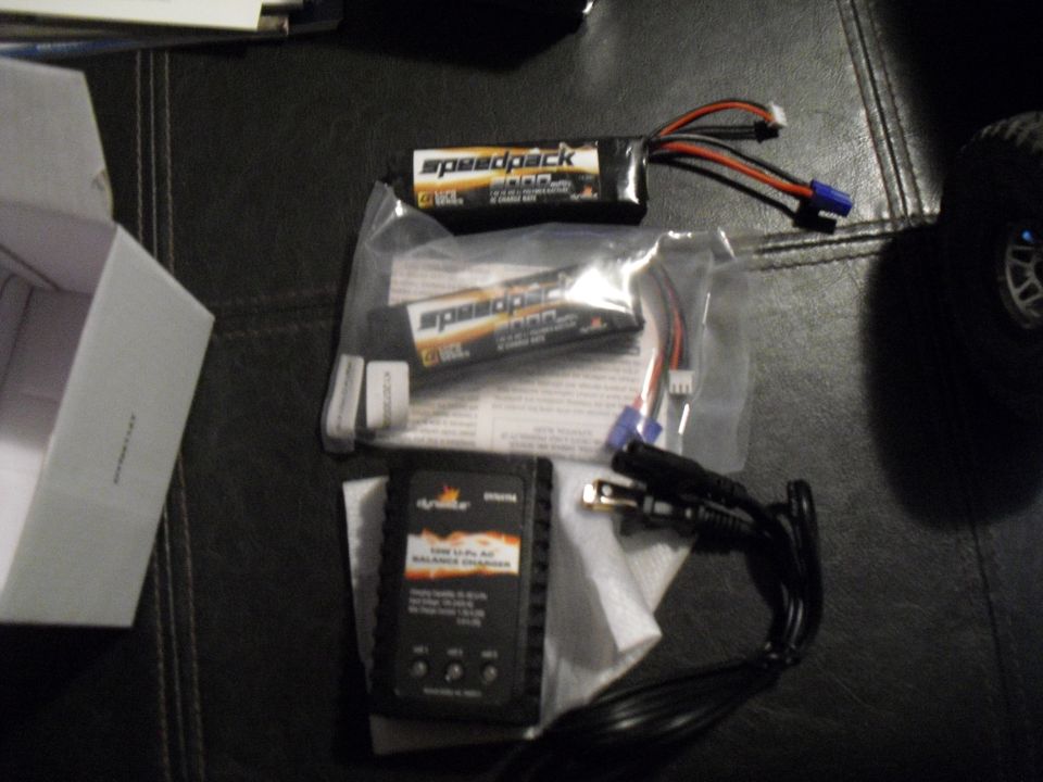 RC car battery charger and two Speedpack batteries on a dark surface