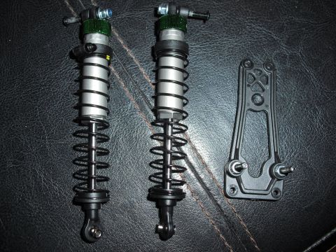 1986 Ford Bronco - Pair of RC car shock absorbers and a mounting bracket are displayed on a dark background.