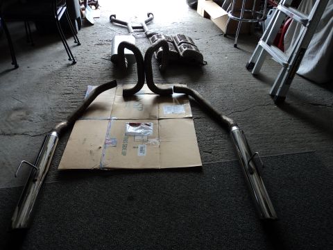 2004 Mercury Grand Marquis - Exhaust system components, including mufflers and pipes, are arranged on a cardboard sheet on a garage floor.