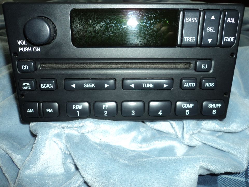 Car stereo head unit with CD slot, volume knob, and buttons for AM/FM, Seek, Tune, Bass, Treble, and Fade
