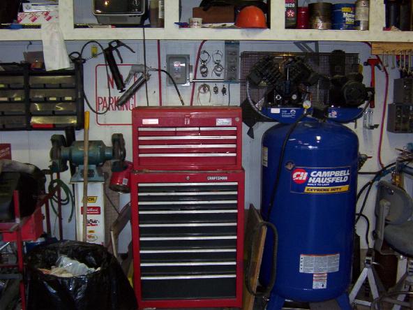 Garage scene with red tool chests, a blue air compressor, and various tools on shelves