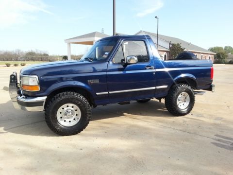 1995 Ford Bronco - This blue 1995 Ford Bronco is shown from the side, aftermarket wheels and a bull bar on the front bumper.