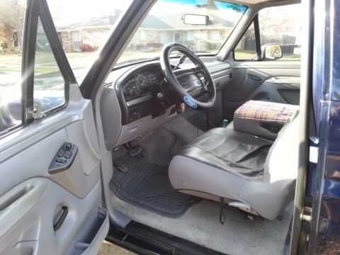 1995 Ford Bronco - The interior of a blue Ford truck, likely from the early to mid-1990s, is viewed from the passenger side.