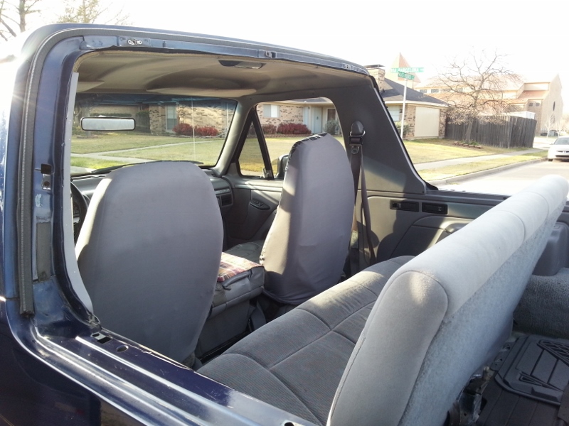 Interior of a blue 1995 Ford Bronco with top removed, showing front and rear seats