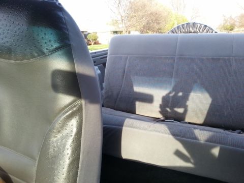 1995 Ford Bronco - Interior view of a vehicle's back seat and part of the driver's seat, with a spare tire cover visible.