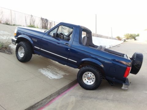 1995 Ford Bronco - This blue 1995 Ford Bronco is shown in a side profile, with its top removed, parked on an incline.