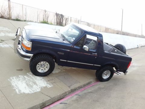 1995 Ford Bronco - This Ford Bronco is parked on a sloped concrete surface with a chain-link fence in the background.