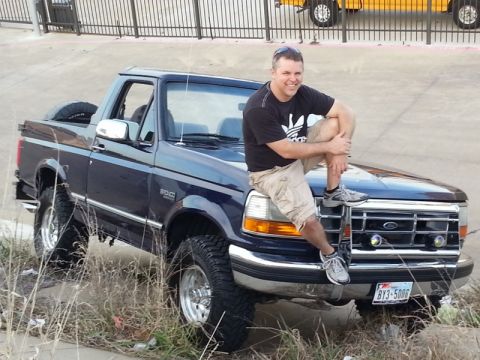 1995 Ford Bronco - Man poses on the hood of a 1995 Ford Bronco.