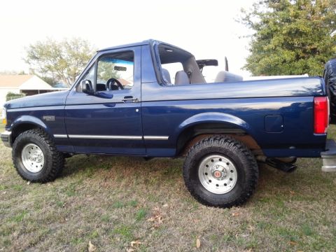1995 Ford Bronco - This blue Ford Bronco convertible is shown from the side, off-road tires and chrome accents.