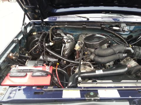 1995 Ford Bronco - Engine bay of a 1995 Ford Bronco, showing the battery, hoses, and engine components.