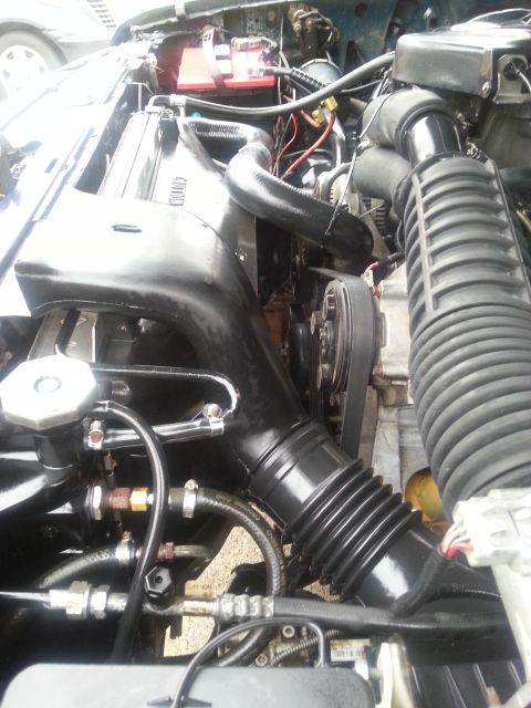 1995 Ford Bronco - The engine bay of a 1995 Ford Bronco shows its internal components, including the radiator and battery.