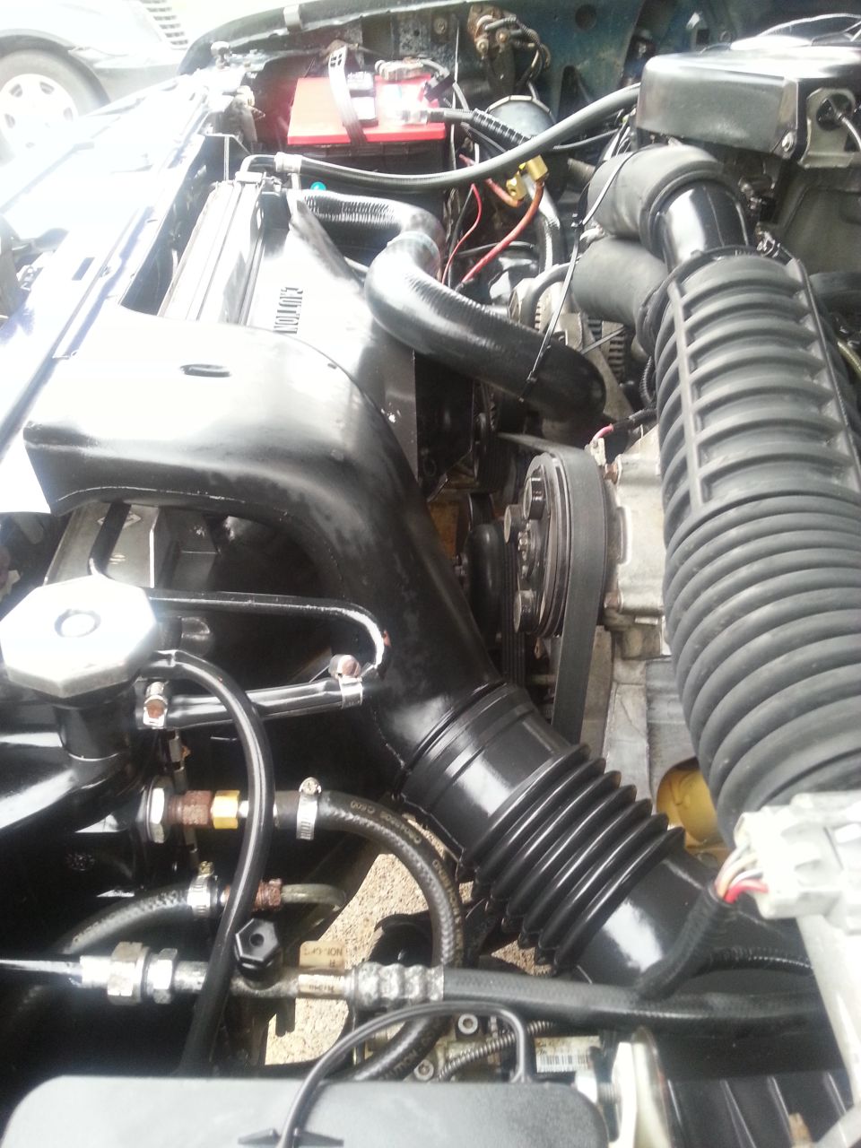 1995 Ford Bronco engine bay with black intake hoses, radiator, and battery