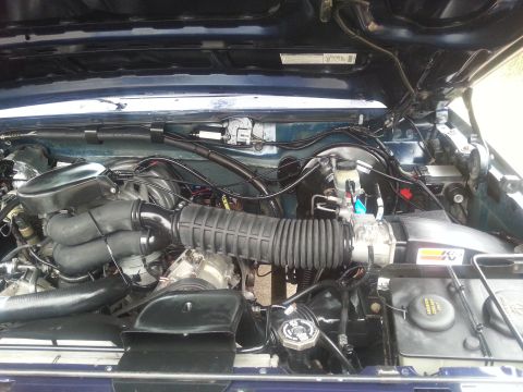 1995 Ford Bronco - The engine bay of a 1995 Ford Bronco is captured, revealing the air intake system and various engine parts.