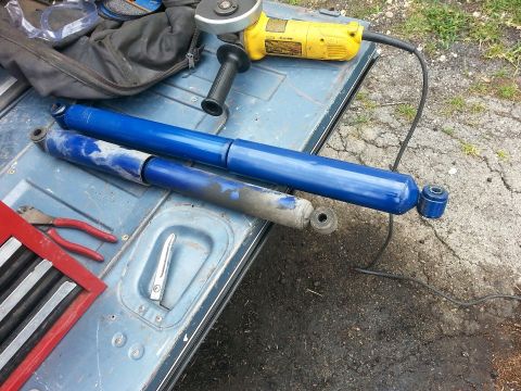 1982 Jeep Wagoneer - New and old shock absorbers are laid out with tools on a vehicle's tailgate, ready for work.