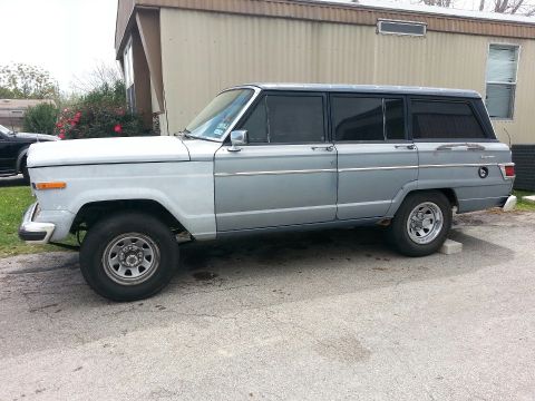 1982 Jeep Wagoneer - This Jeep Grand Wagoneer is parked on a paved surface in front of a building.