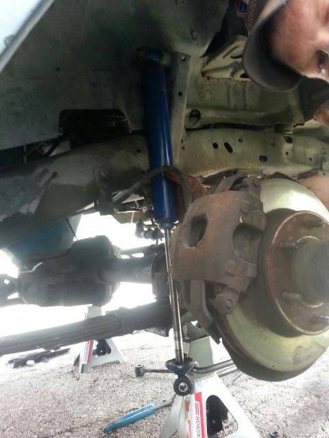 1982 Jeep Wagoneer - Close-up view of the front suspension and brake assembly, showing a blue shock absorber and disc brake components.