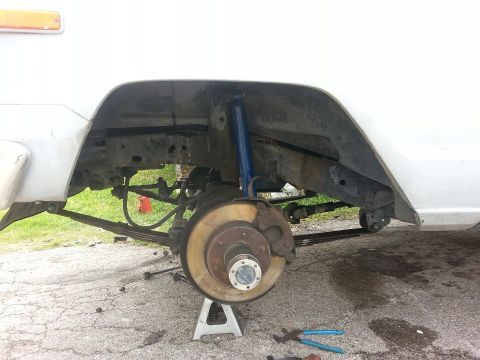1982 Jeep Wagoneer - The rear suspension of a 1982 Jeep Wagoneer is shown, with the wheel removed and the axle supported by a jack stand.