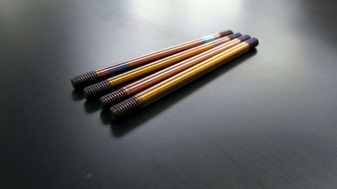 1996 Ford Bronco - A group of four threaded metal rods, exhibiting iridescent heat-treated coloring, lie on a dark surface.