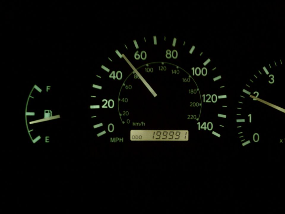 Car dashboard with fuel gauge and speedometer showing 199,991 miles on odometer
