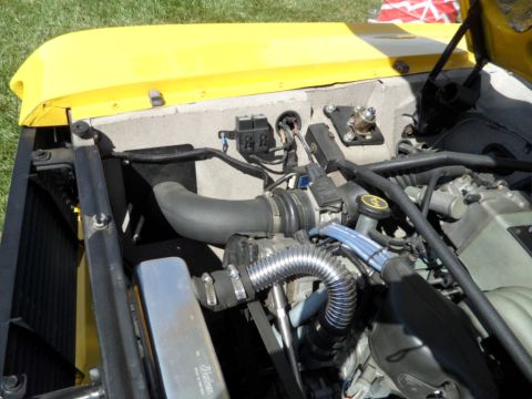 1973 Ford Ranchero - A close-up view of the engine bay, showing various components and wiring under the hood of a yellow vehicle.