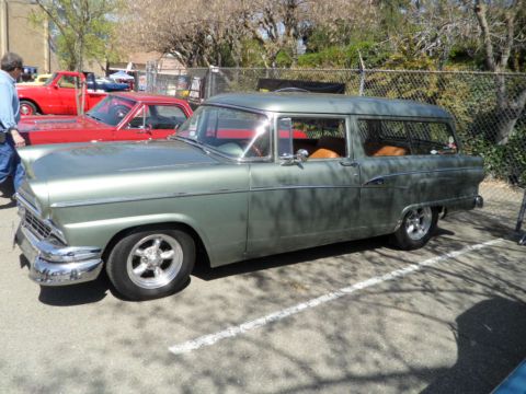 1973 Ford Ranchero - A green station wagon with custom wheels is parked at a car show next to a red pickup truck.