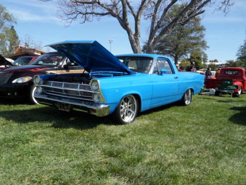 1973 Ford Ranchero - A bright blue pickup truck, possibly a 1966 model, is displayed with its hood open at a car show.