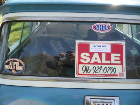 1973 Ford Ranchero - A "For Sale" sign with a phone number is displayed on the rear window of a vehicle, alongside various stickers.