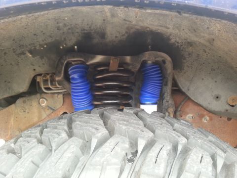 1995 Ford Bronco - The front suspension system, blue shock boots and a coil spring, is visible above a large tire.