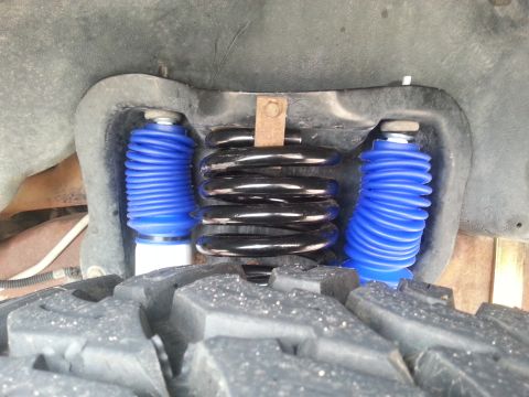 1995 Ford Bronco - Vehicle suspension system with blue shock absorbers and black coil springs is viewed from a close-up angle.