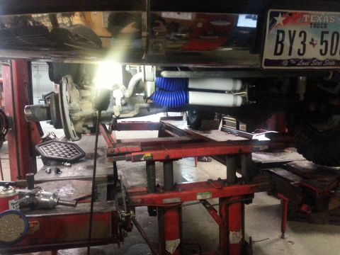 1995 Ford Bronco - Truck's rear suspension system with added air shocks, seen on a lift in a garage.