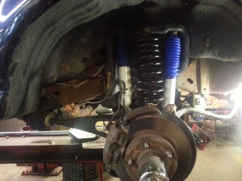 1995 Ford Bronco - The front suspension and brake components of a vehicle are shown, including a coil spring and blue shock absorber.