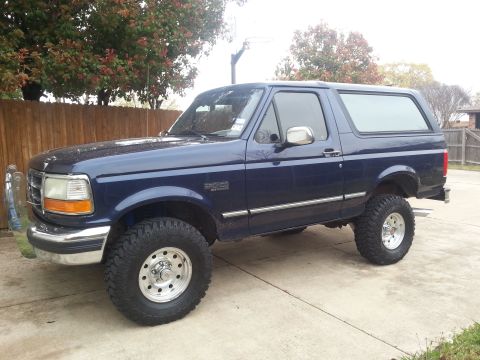 1995 Ford Bronco - Side view of a blue 1995 Ford Bronco with aftermarket wheels and tires.