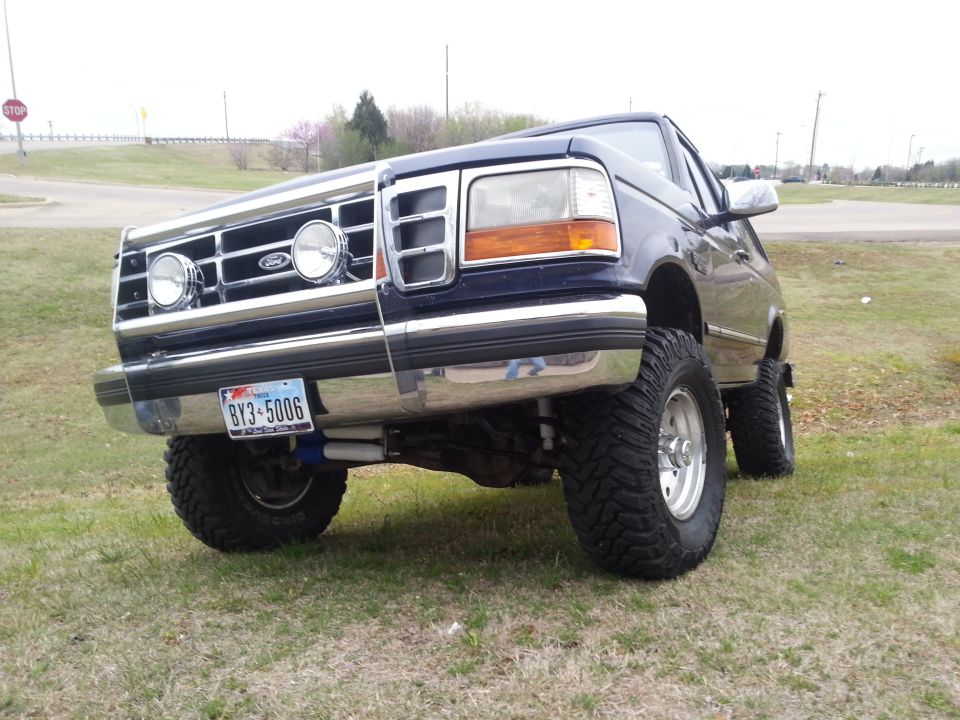 Dark blue Ford Bronco with lifted suspension and large tires, viewed from a low front 3/4 angle