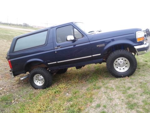 1995 Ford Bronco - This blue 1995 Ford Bronco is shown from a 3/4 front angle on a grassy hill.