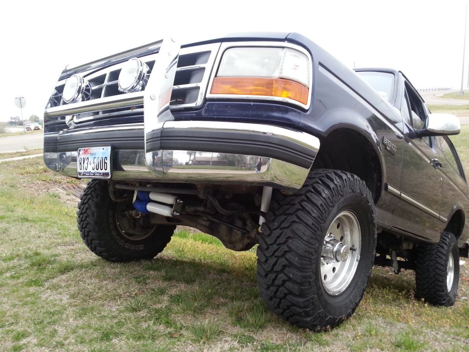 Blue Ford Bronco with a brush guard and lifted suspension. License plate reads 8Y3-5006