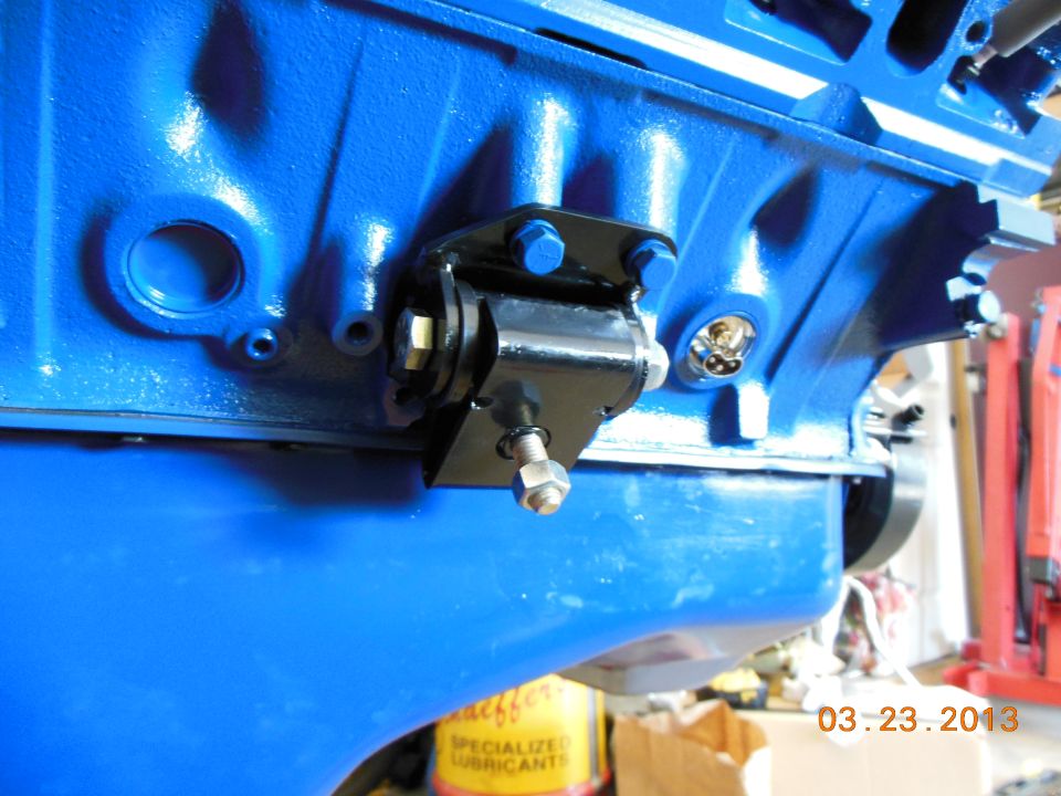 Blue painted engine block with black motor mount attached. Yellow can with text visible in background
