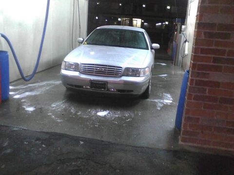 2003 Ford Crown Victoria - A silver 2003 Ford Crown Victoria is parked in a car wash bay, with suds on the floor.