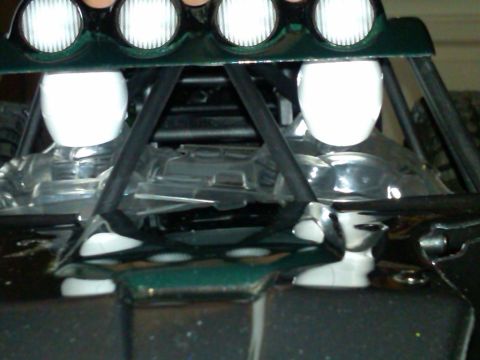 1986 Ford Bronco - The interior of a custom off-road vehicle is shown, a roll cage and auxiliary lighting.