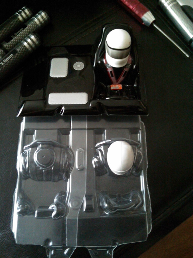 Toy car interior parts and driver figure in plastic packaging with tools